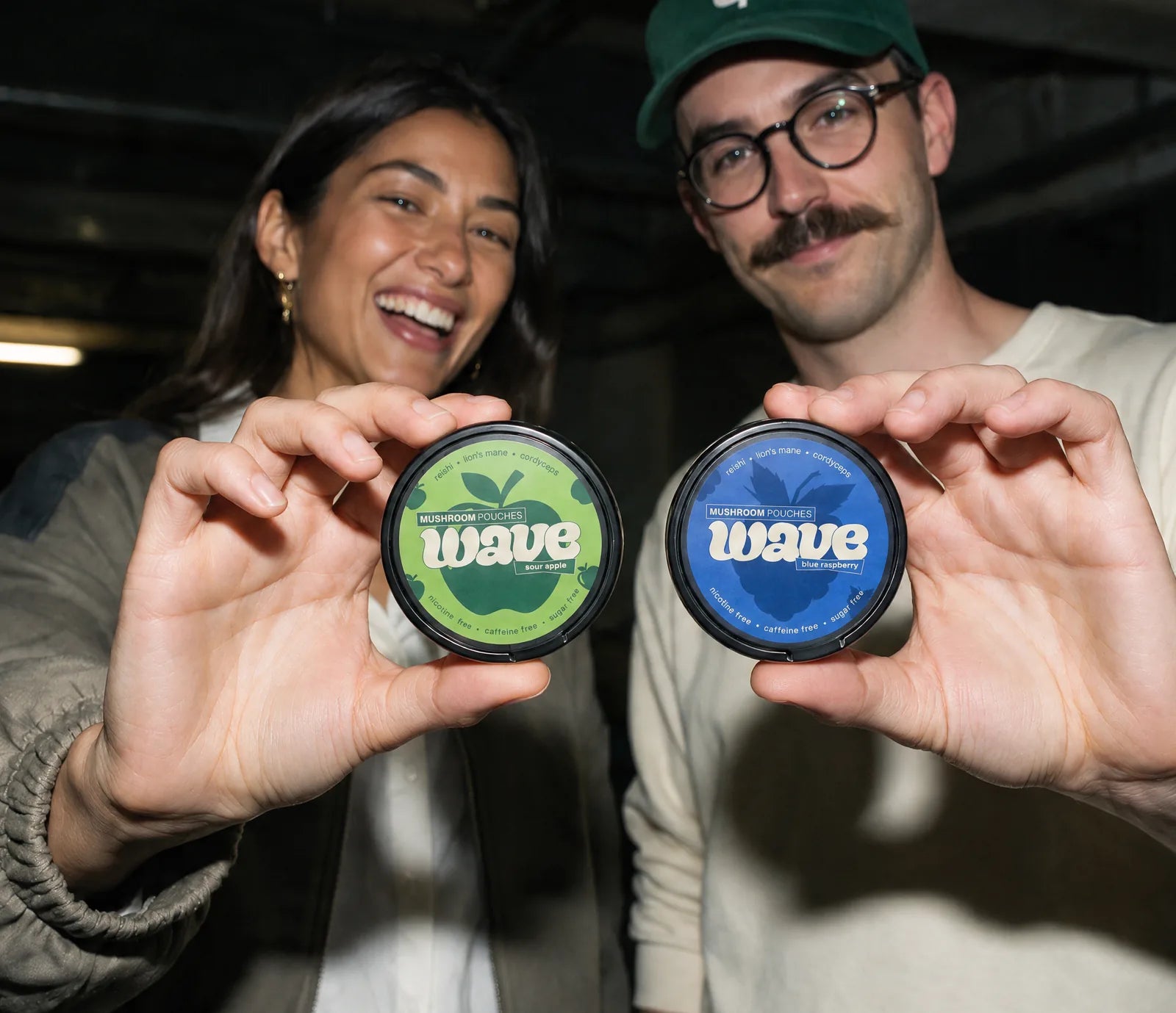 Twee vrienden in een garage houden een WAVE-blikje Sour Apple en een blikje Blue Raspberry voor de camera