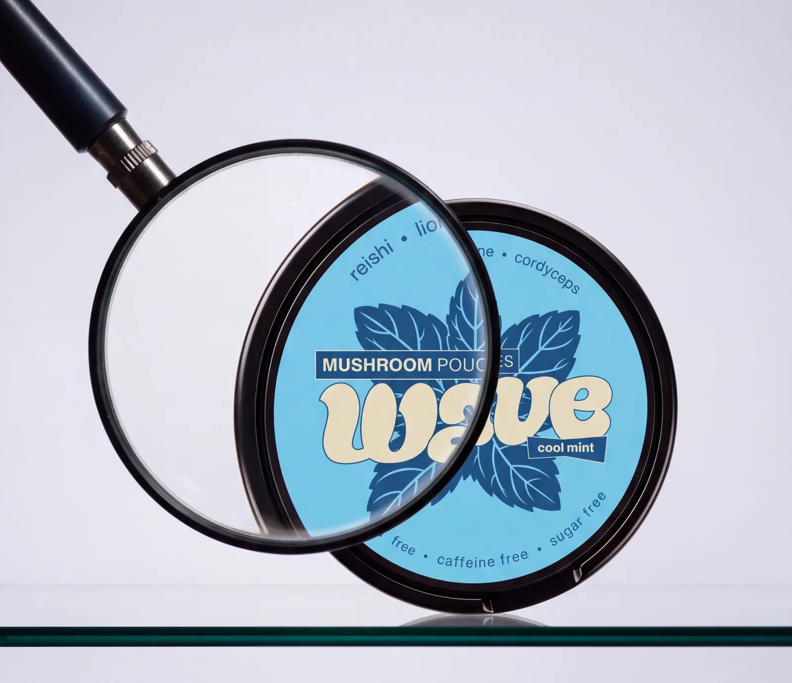 Een vergrootglas boven een WAVE-blikje Cool Mint op een glazen plank